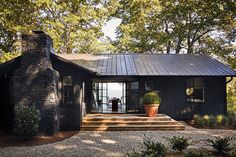 a black house with steps leading up to the front door and entry way, surrounded by trees