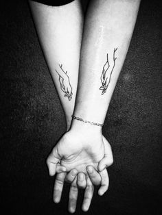 two hands holding each other with tattoos on them