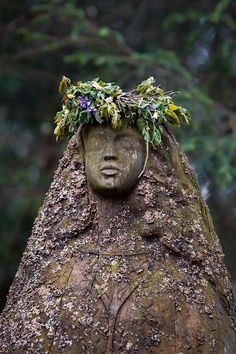 a tree with a face carved into it's trunk and flowers growing out of its head