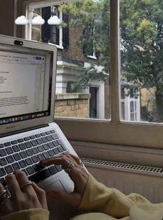 a person typing on a laptop in front of a window