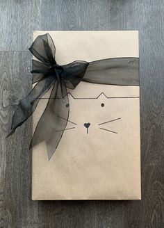 a piece of paper with a cat's face drawn on it and a black bow