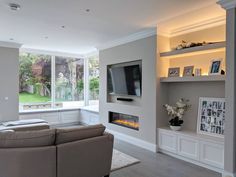 a living room filled with furniture and a flat screen tv mounted on a wall above a fire place