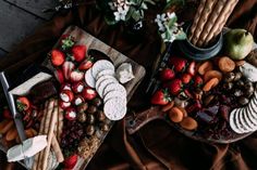 two trays filled with cheese, crackers and strawberries next to each other