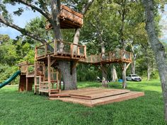 a tree house built into the side of a large tree in a grassy area with a slide