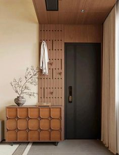 a room with a large wooden cabinet next to a black door and brown curtains on the wall