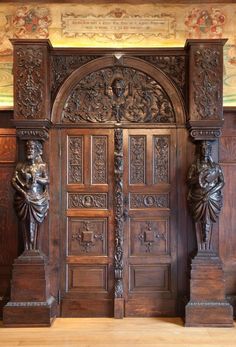 an ornate wooden door with statues on either side