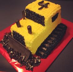 a cake that is shaped like a construction truck on a red plate with black icing