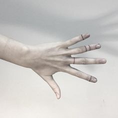 a person's hand with rings on it is reaching out to the sky in front of a white background