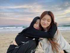 two girls hugging each other on the beach