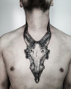 a man's chest with a cow skull tattoo on the upper part of his neck