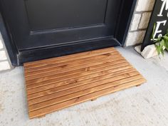 a wooden floor mat sitting in front of a door