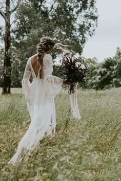 a woman in a wedding dress walking through tall grass