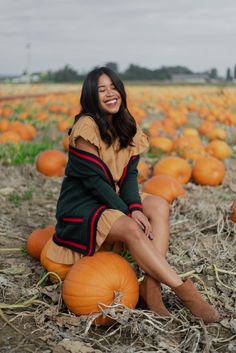 a woman sitting on top of a pumpkin field