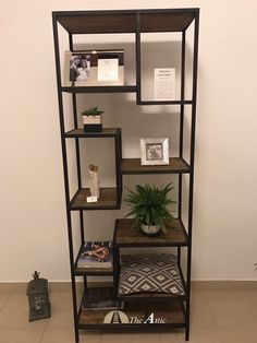 a shelf with books, plants and pictures on it in the corner of a room