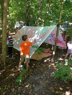 three children playing in the woods with a tent