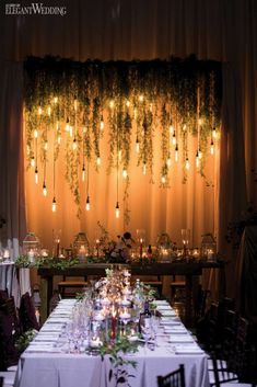 the table is set up with candles and greenery for an outdoor wedding reception at night