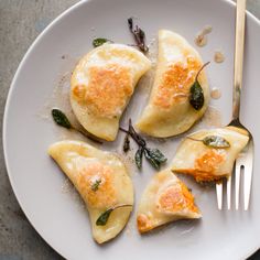 four ravioli with spinach and cheese on a white plate next to a fork