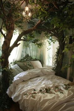 a bed with white sheets and pillows under a tree