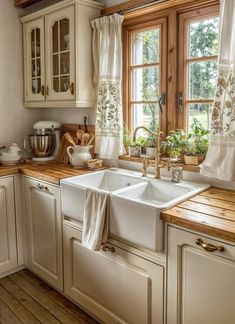 a kitchen with white cabinets and wooden counter tops next to a window filled with potted plants