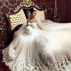 a woman in a wedding dress sitting on a bed