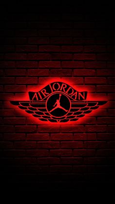 the air jordan logo is lit up on a brick wall with red light behind it