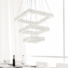 a chandelier hanging from the ceiling over a dining room table with white chairs