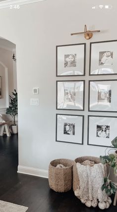 a living room with pictures on the wall and two large baskets in front of it