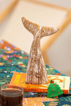 a small wooden whale tail sitting on top of a table next to books and candles