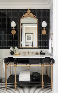 a black and white bathroom with gold trimmings on the mirror, sink, and vanity