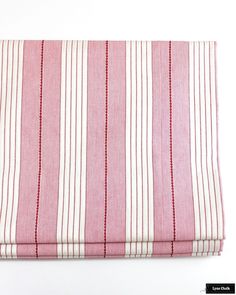 the pink and white striped fabric is folded on top of each other with red trim