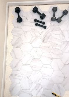 there are some black and white knobs on the marble wall in this bathroom with hexagon tiles