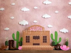 there is a pink wall with cactus and cowboy boots on the shelf next to it