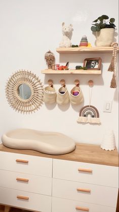 a white dresser topped with lots of drawers and shelves next to a wall mounted mirror