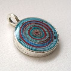 a silver pendant with red, blue and green designs on it's back end