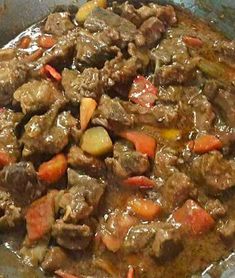 meat and vegetables are being cooked in a skillet