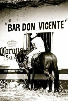 a man riding on the back of a brown horse next to a white and black building