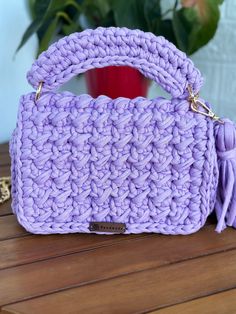 a purple crocheted purse sitting on top of a wooden table