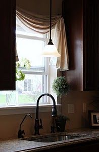 a kitchen sink under a window next to a counter top with a potted plant on it