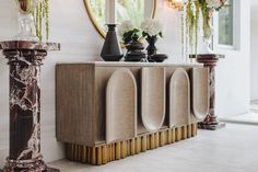 an art deco sideboard with vases and flowers on it in front of a mirror