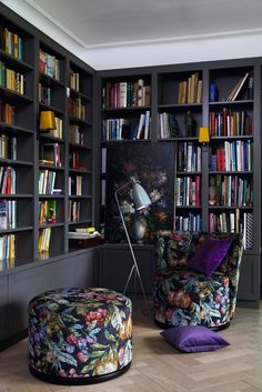 a living room filled with lots of bookshelves covered in colorful furniture and decor