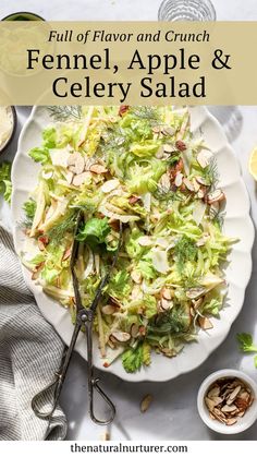 a white plate topped with a salad next to a bowl of nuts and lemons