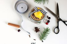 scissors, tape and pine cones are sitting on the table next to some christmas decorations