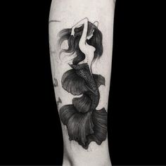 a black and white photo of a woman's leg with a fish tattoo on it