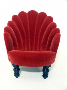 a red chair sitting on top of a white floor next to a black leg rest