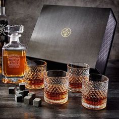 four whiskey glasses sitting next to an empty bottle