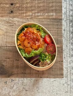 a wooden table topped with a bowl filled with salad and shrimp on top of lettuce