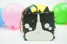 a black and white cat purse with balloons in the background