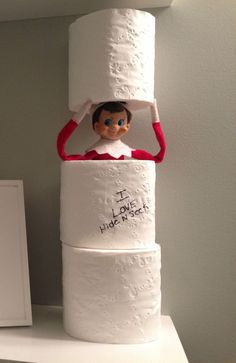 a elf on top of three rolls of toilet paper