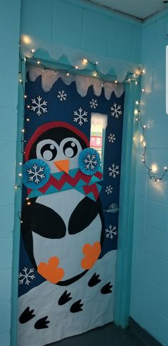 a door decorated to look like a penguin with lights around it and snowflakes hanging from the ceiling