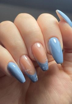 a woman's hand with some blue and beige nail polishes on her nails